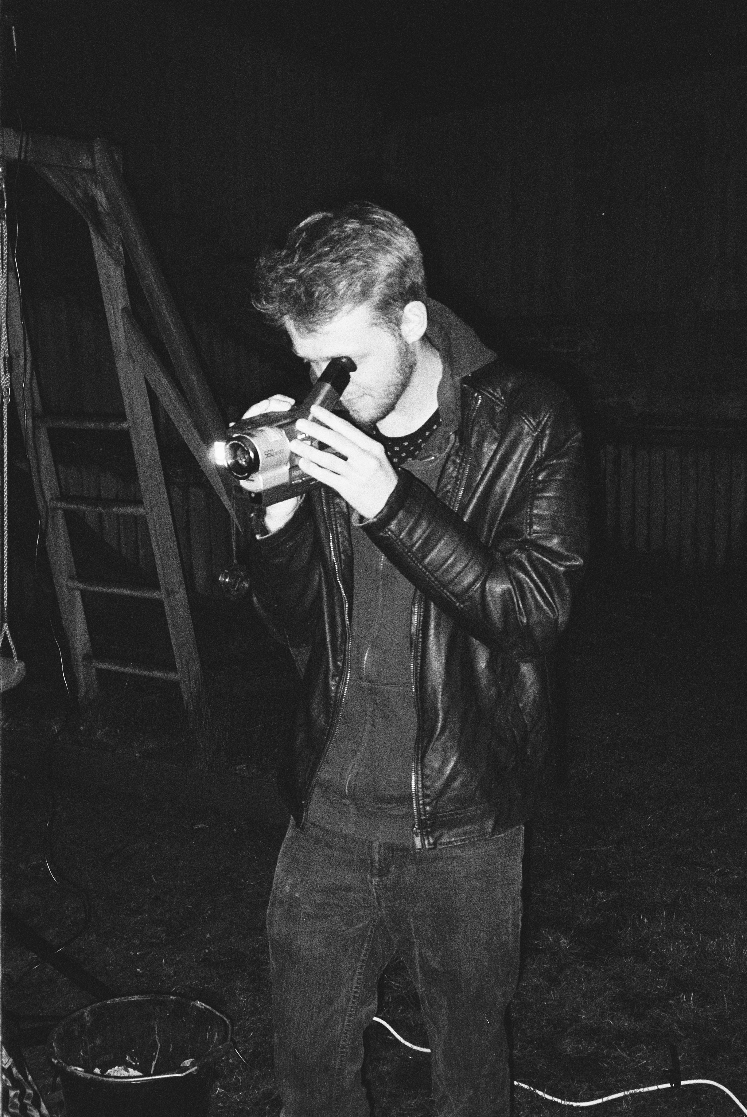 man in black leather jacket holding black dslr camera